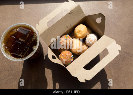 Une boîte de beignets servis avec un café glacé à un restaurant Tim Hortons au Canada. Les Timbits sont, essentiellement, des morceaux de beignets. Banque D'Images
