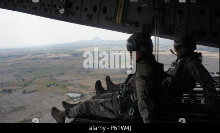 Deux aviateurs, profiter de la vue hors de la porte arrière d'un C-17 Globemaster III au cours d'une manoeuvre à basse altitude réalisées pendant l'exercice Balikatan 2016, Clark Air Field, Philippines, le 15 avril 2016. L'avion a été affecté par les aviateurs de l'Hawaii Air National Guard's 204e Escadron de transport aérien et service actif 535e Escadron de transport aérien. Balikatan, ce qui signifie 'shoulder à assumer' en espagnol, est un exercice d'entraînement bilatéral annuel visant à améliorer la capacité des forces militaires des États-Unis et des Philippines à travailler ensemble lors de la planification d'urgence, et l'aide humanitaire et secours en cas de catastrophe ope Banque D'Images