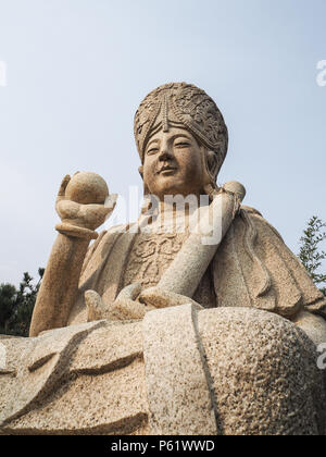 Qingdao, Chine - Décembre 2017 : blanc sculpture bouddhiste sculpté tenant un ballon et faites défiler jusqu'à l'entrée de Yanku scenic area at Mt. Yuxi Banque D'Images