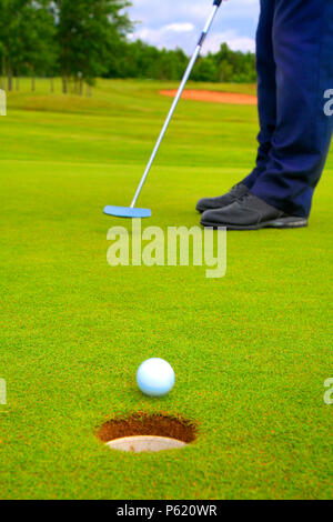 Fermer la vue d'une balle de golf à côté d'une tasse sur le vert. Banque D'Images