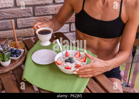 Femme Fitness ont un petit-déjeuner. Maison saine du gruau aux fruits rouges Banque D'Images