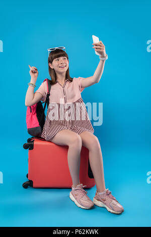 Heureux fille assise sur ses bagages Banque D'Images