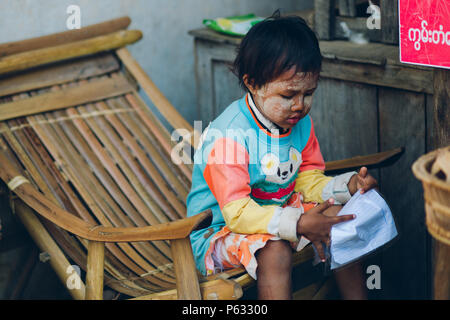 Bagan, Myanmar - 21 févr. 2014 : Portrait de jeune fille birmane la lecture à la maison comme une boutique locale Banque D'Images