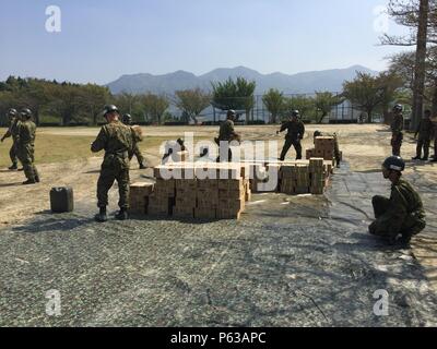 Forces d'autodéfense japonaises membres de services d'aide aux victimes du séisme de la pile des articles qui ont été déchargées d'un MV-22B Balbuzard appartenant au milieu marin de l'Escadron 265 rotor basculant (renforcée), 31e Marine Expeditionary Unit, 19 avril 2016 à Hakusui Sport Park, Kumamoto, Japon. 31e MEU marines sont des JSDF secours par suite des tremblements de terre qui a frappé l'île de Kyushu au début de la semaine, à la demande du Gouvernement du Japon. La 31e MEU est le seul de l'avant sans cesse déployés-MEU et demeure la force du Marine Corps en préparation dans la région Asie-Pacifique. (U.S. C Marine Banque D'Images