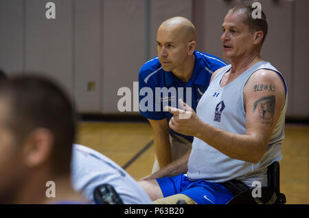 Le major (Dr.) Sean Martin, le chef de la médecine du sport avec de l'Air Force Special Operations Command bureau du Surgeon General, parle à pris sa retraite Tech. Le Sgt. Pat Young, un athlète blessé-guerrier, au cours de la pratique de basket-ball en fauteuil roulant à Hurlburt Field, en Floride, le 5 avril 2016. Martin et autres techniciens médicaux fournissent des services supplémentaires pour les athlètes pendant le camp d'entraînement afin d'assurer autant que possible de leur temps est consacré à la compétition et non pas sur la ligne de côté. (U.S. Photo de l'Armée de l'air par le sergent. Marleah Miller) Banque D'Images