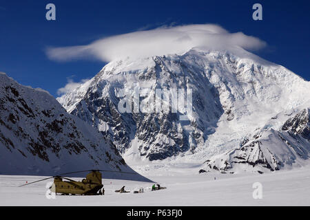 Le mont Foraker (17 400 pieds) au-dessus des soldats de la Compagnie B, 1er Bataillon, 52e Régiment d'aviation comme ils décharger du matériel et fournitures auprès du CH-47F Chinook après l'atterrissage sur le Glacier Kahiltna. Trois équipages de l'aviation en Alaska l'armée américaine Groupe d'étude a passé la semaine à Talkeetna, Alaska, la formation en haute altitude de vol dans la chaîne de l'Alaska. La mission pour le dimanche, 24 Avril inclus poursuivent un partenariat de longue date avec le National Park Service navette pour le matériel et les fournitures nécessaires pour le Service des parcs camp de base sur le Glacier Kahiltna pour la prochaine saison d'escalade sur Den Banque D'Images