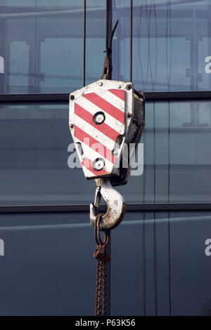 Peint en rouge et blanc de bloc de levage crane, affichage de plusieurs bureaux de verre et de câble derrière. Banque D'Images