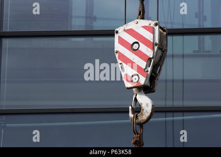 Peint en rouge et blanc de bloc de levage crane, affichage de plusieurs bureaux de verre et de câble derrière. Banque D'Images