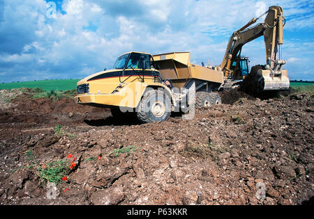 Le décapage de la terre végétale de l'excavateur à côté de la route. Dérivation de Baldock, sur l'A505, Hertfordshire, Angleterre. La nouvelle voie de contournement impliqués de plus d'un million de m3 s'est réuni Banque D'Images