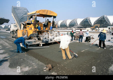 Machine de pavage en béton et de l'équipage qui travaillent sur l'hardstand pour les avions près de l'aérogare à l'aéroport de Bangkok Suvarnabhumi Banque D'Images