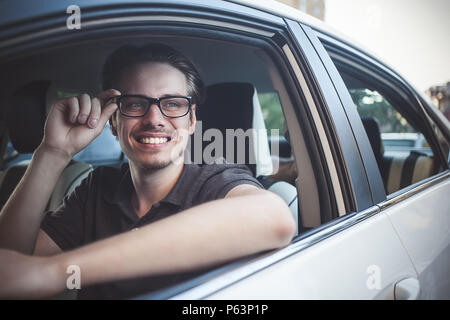 Profitez de la route. Image de jeune beau mec assis en voiture. Banque D'Images