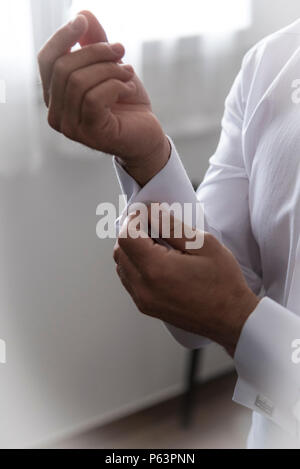 Un groom mettant sur boutons de manchettes qu'il sera habillé de l'usure. Costume du marié Banque D'Images