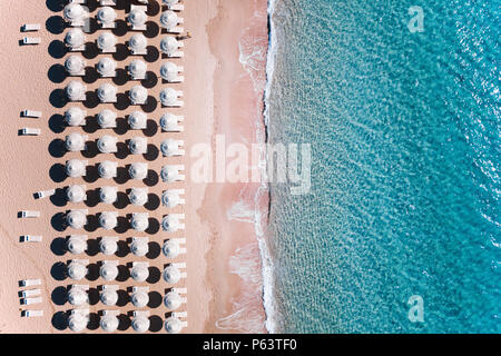 Vue aérienne de la mer turquoise magnifique avec parasols blancs et des chaises longues. Belle journée ensoleillée en Sardaigne, mer Méditerranée, l'Italie. Banque D'Images