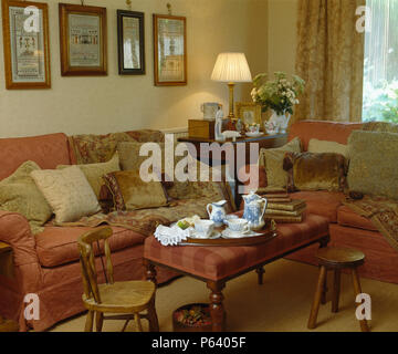 Jeter sur canapé de velours avec des coussins empilés dans maison de ville traditionnelle salon avec plateau situé sur tabouret rembourré Banque D'Images