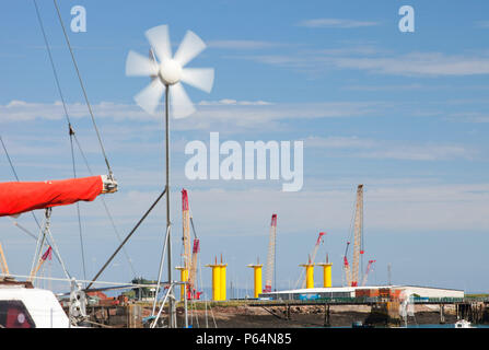 Un yacht avec une petite éolienne en face de la construction site pour Dong Energy's éoliennes en mer. Les tours de jaune sont les fondements fo Banque D'Images