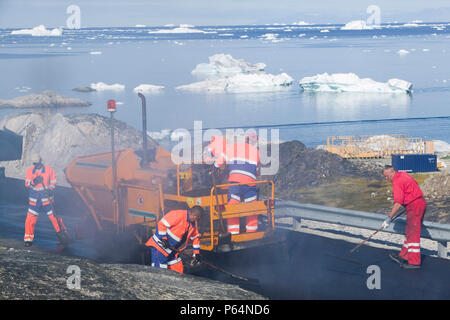 Portant sur une route goudronnée à Ilulissat, au Groenland, avec des icebergs de l'icefjord Jacobshavn derrière Banque D'Images