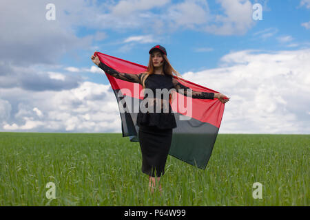 Belle jeune fille ukrainienne avec une excellente figure dans une robe courte noire détient un drapeau noir rouge national ukrainien Banque D'Images