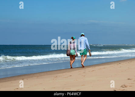 Ein junges, schlankes Paar von hinten, welches am Strand von Rügen spazieren geht.BeIDE tragen mit unternehmberatung und Beide barfuß. Banque D'Images