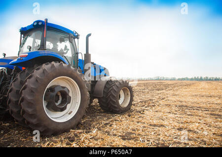 Tracteur bleu sur l'arrière-plan d'un champ vide et un ciel bleu clair Banque D'Images