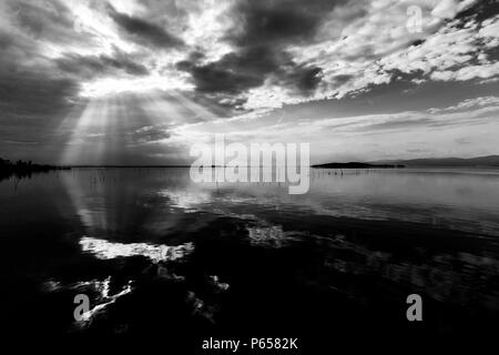 Parfaitement symétrique et vue spectaculaire d'un lac, avec des nuages, le ciel et les rayons du soleil reflétant sur l'eau Banque D'Images