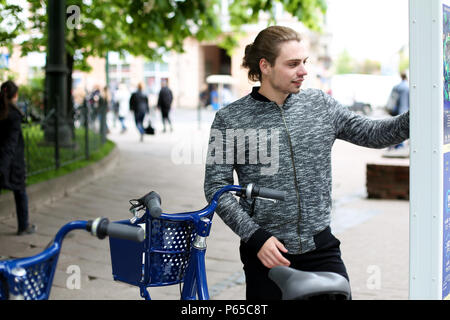 Jeune homme bleu embauche location avec la machine en ville. Banque D'Images