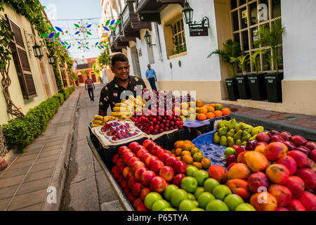 Un fournisseur colombien pousse un chariot chargé de fruits pour la vente sur la rue de Getsemaní, un quartier artistique populaire à Cartagena, Colombie. Banque D'Images