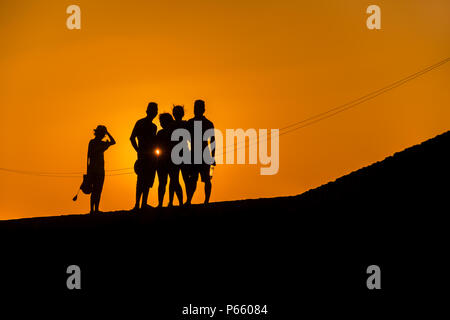 Un groupe de jeunes touristes colombiens regarder le coucher du soleil en marchant sur les murs en pierre entourant la ville fortifiée coloniale à Cartagena, Colombie. Banque D'Images