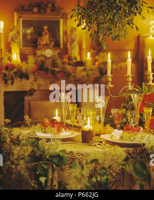 Close-up of salle décorée pour Noël avec le gui suspendue au-dessus de table avec des verres de champagne et bougies Banque D'Images