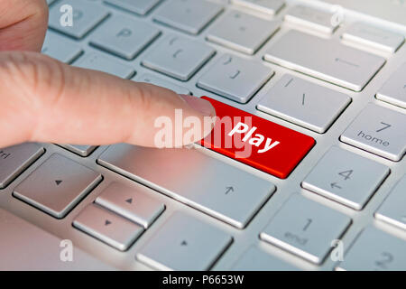 Gros plan d'un doigt en cliquant sur le bouton lecture sur un clavier d'ordinateur portable. , Bouton rouge. Banque D'Images