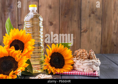 Dodsolnechnoe d'huile dans une grande bouteille, un bouquet de tournesols fleurs, sur un arrière-plan terned. La cuisson à la maison. Biscuits avec les graines. Produit naturel, style rustique. Copy space Banque D'Images