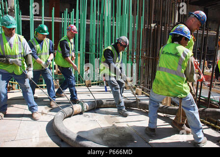 Les travailleurs le flexible de la pompe à béton dans la tour un site, Lower Manhattan, New York City, USA Banque D'Images