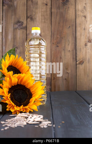 Dodsolnechnoe d'huile dans la bouteille, un bouquet de tournesols fleurs, sur un arrière-plan terned et graines dispersées. Produit naturel, style rustique. Copy space Banque D'Images