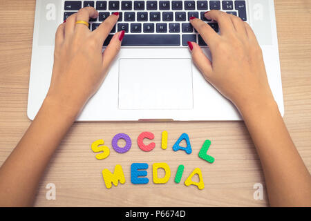 Femme d'affaires la main à l'aide d'un ordinateur portable avec les médias sociaux social media concept , lettres Banque D'Images
