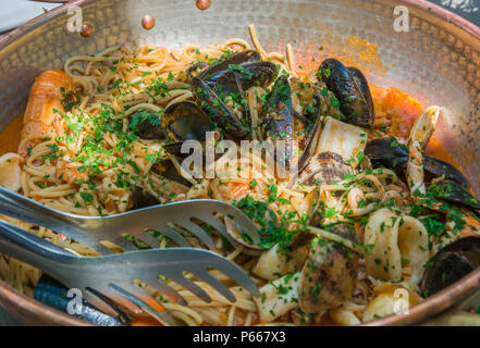 Spaghetti aux moules et seiche juste servi dans la marmite en cuivre. une cuisine traditionnelle du sud de l'Italie. Selective focus Banque D'Images