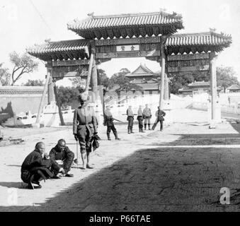 Au cours de l'est en pont vers la Cité Interdite, Pékin, 1901. tirage photographique sur carte stéréo, soldats indiens et deux hommes chinois en face d'une porte. Banque D'Images