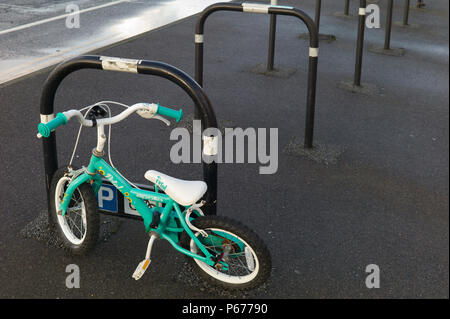 L'enfant bicyclette verte au parc de vélo vide Banque D'Images