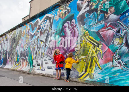 30 juin 2017 : Les enfants se tient en dehors de la peinture et Graffiti sur l'Eastside Gallery de Berlin, Allemagne. Banque D'Images