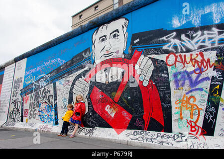 30 juin 2017 : Les enfants se tient en dehors de la peinture et Graffiti sur l'Eastside Gallery de Berlin, Allemagne. Banque D'Images
