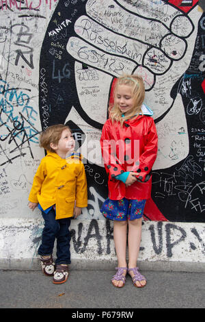 30 juin 2017 : Les enfants se tient en dehors de la peinture et Graffiti sur l'Eastside Gallery de Berlin, Allemagne. Banque D'Images