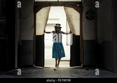 Jeune femme en bleu clair jupe et l'ouverture d'une porte en place abandonnée. Banque D'Images