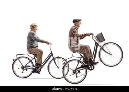 Les personnes âgées la bicyclette avec l'un d'eux en faisant un wheelie isolé sur fond blanc Banque D'Images