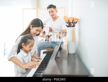 La famille asiatique, la mère et la fille joue du piano,père jouer de la guitare dans family band à la maison, concept de relation familiale Banque D'Images