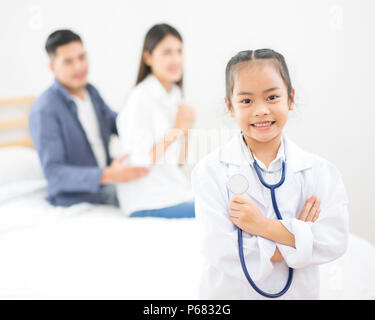 Peu de médecin, jolie petite fille asiatique habillé comme un médecin à la maison Banque D'Images