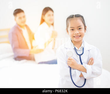 Peu de médecin, jolie petite fille asiatique habillé comme un médecin à la maison Banque D'Images