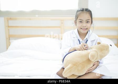 Peu de médecin, jolie petite fille asiatique habillé comme un médecin à la maison Banque D'Images