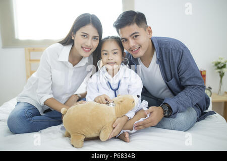 Peu de médecin, jolie petite fille asiatique habillé comme un médecin à la maison Banque D'Images