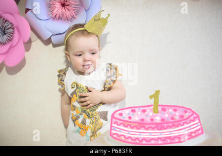 Petite fille est à la recherche d'un gâteau avec une bougie pour un an Banque D'Images