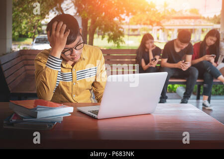 L'homme a souligné tout en travaillant sur un ordinateur portable, jeune homme stressé, a souligné à l'école secondaire des étudiants assis au bureau Banque D'Images