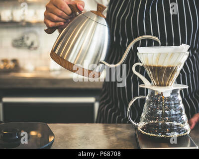 Café filtre, café barista part verser l'eau chaude de la bouilloire sur le café en poudre. Banque D'Images