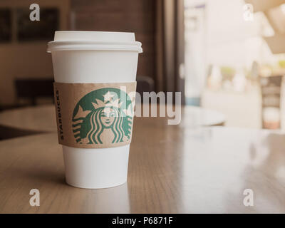 Samut Songkhram, THAÏLANDE - 21 juin 2018 : un café chaud en plastique blanc tasse à café à emporter sur table en bois à côté de la fenêtre en verre dans le Starbucks C Banque D'Images